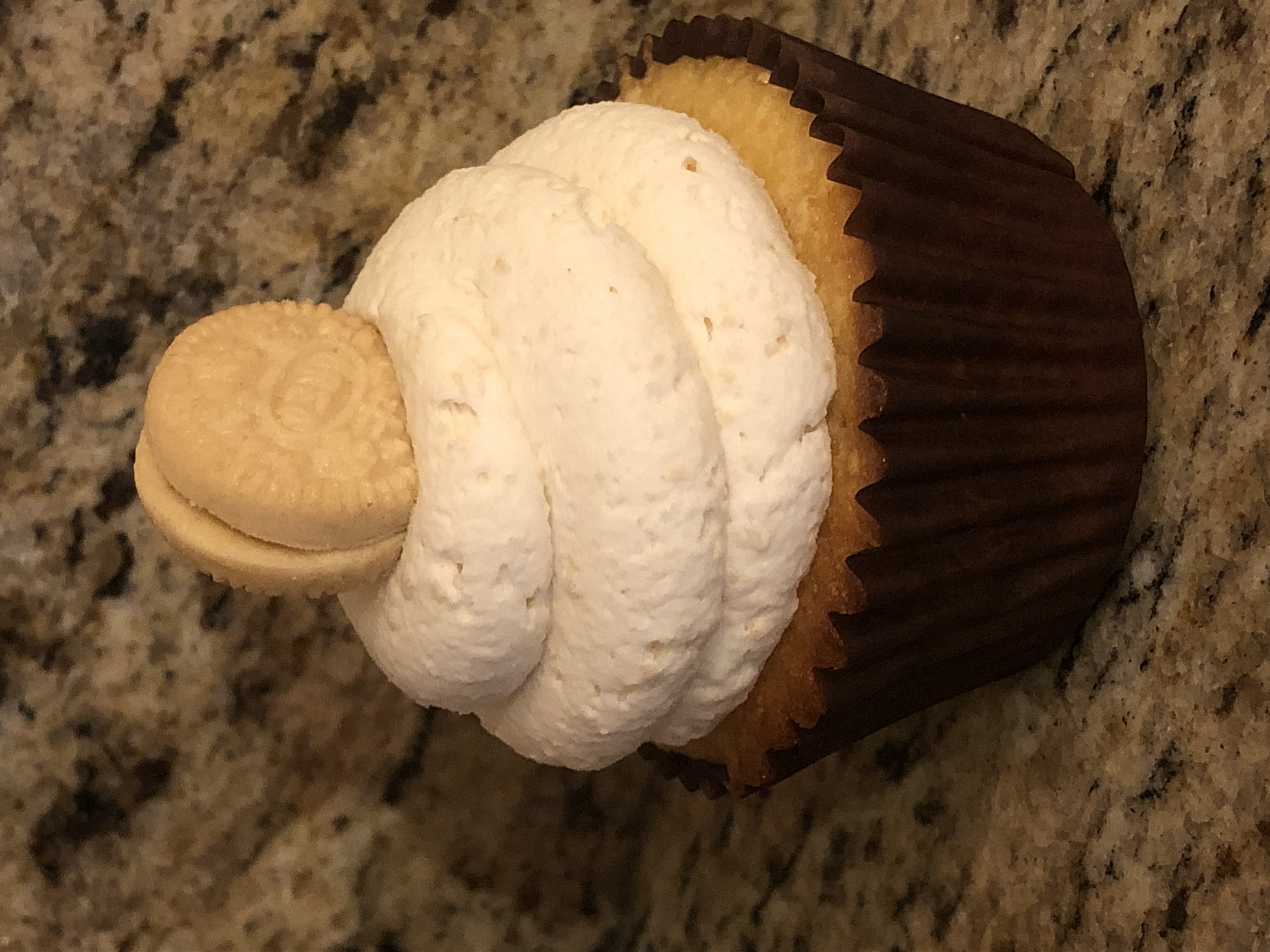 Vanilla cupcake with swirled white buttercream frosting and a mini sandwich cookie garnish