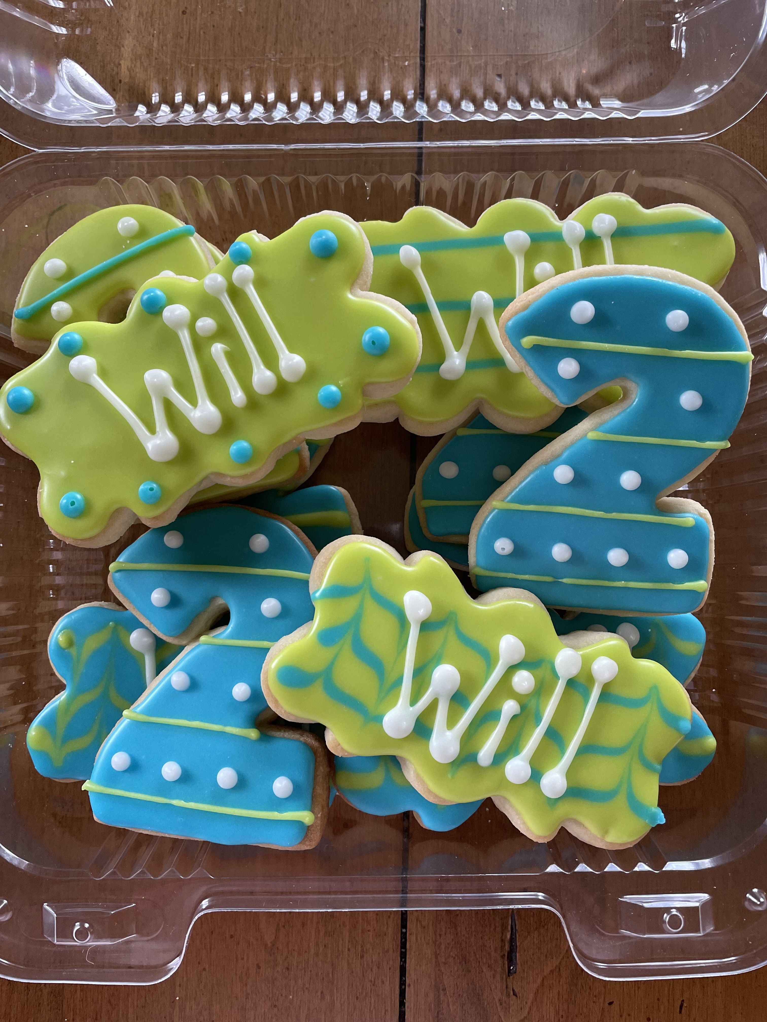 Custom iced sugar cookies shaped as the number 2 and the name Will, decorated in blue and green royal icing