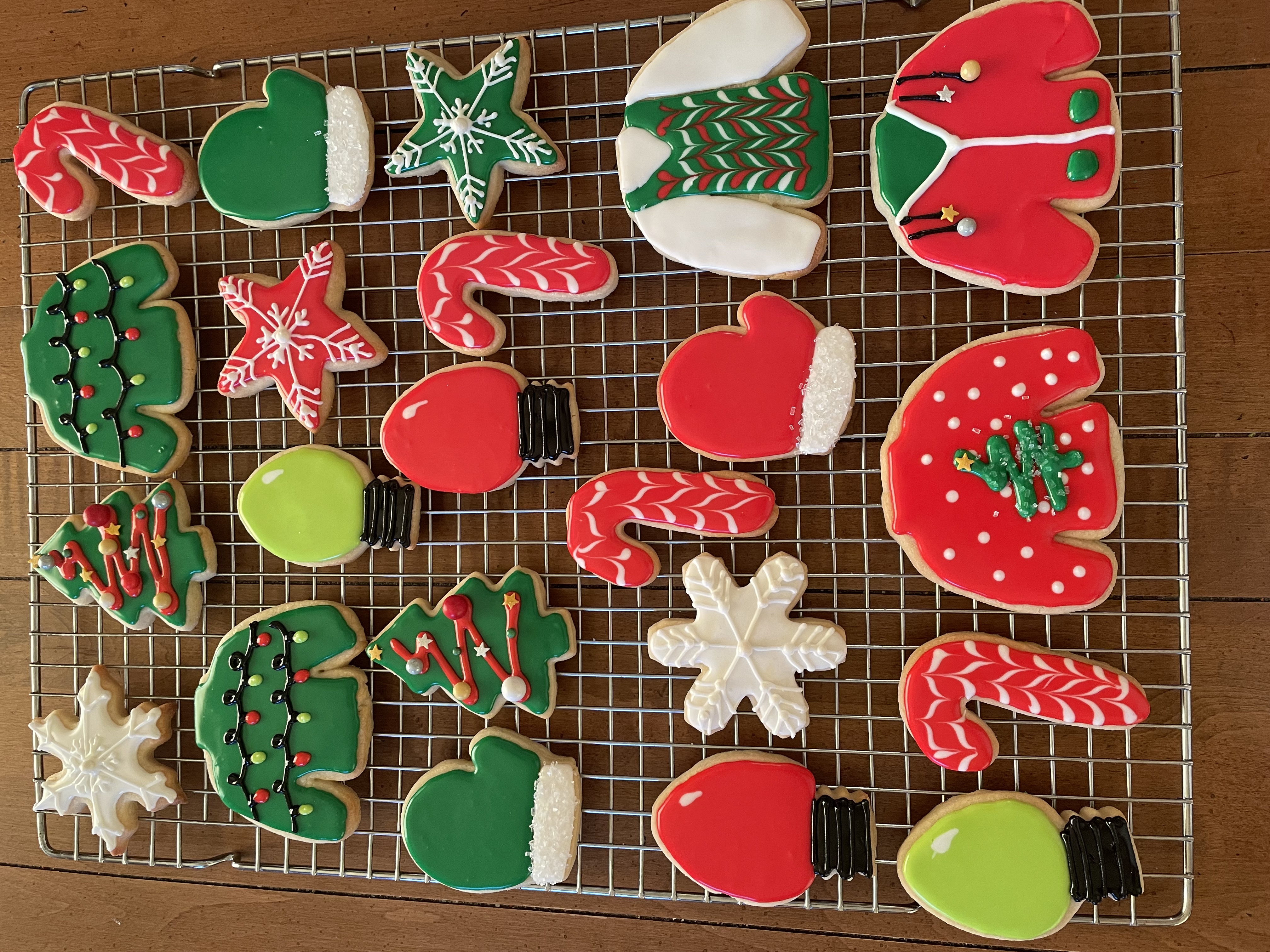 Assortment of Christmas-themed iced sugar cookies including mittens, stars, trees, candy canes, and ornaments in red and green