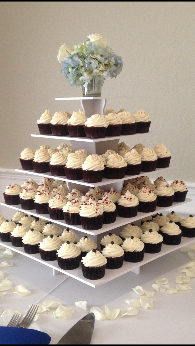Four-tier cupcake tower display with chocolate cupcakes topped with swirled vanilla cream frosting